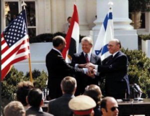 Guided by President Jimmy Carter, Israeli Primer Minister Menachem Begin and Egyptian President Anwar Sadat shake hands on the White House lawn, 1979.